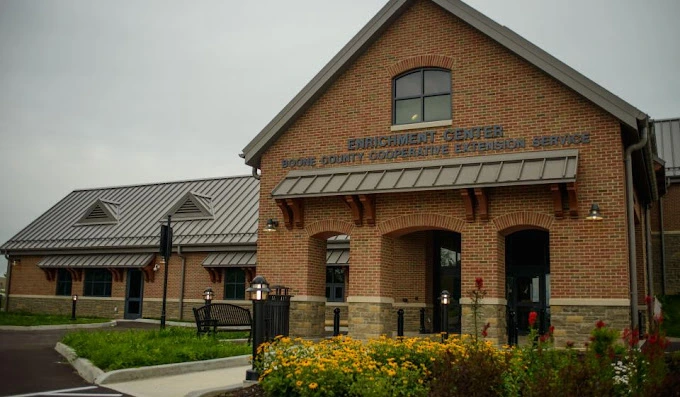Exterior photo of the boone county Extension Enrichment Center building. Reddish brick walls with a metal roof.